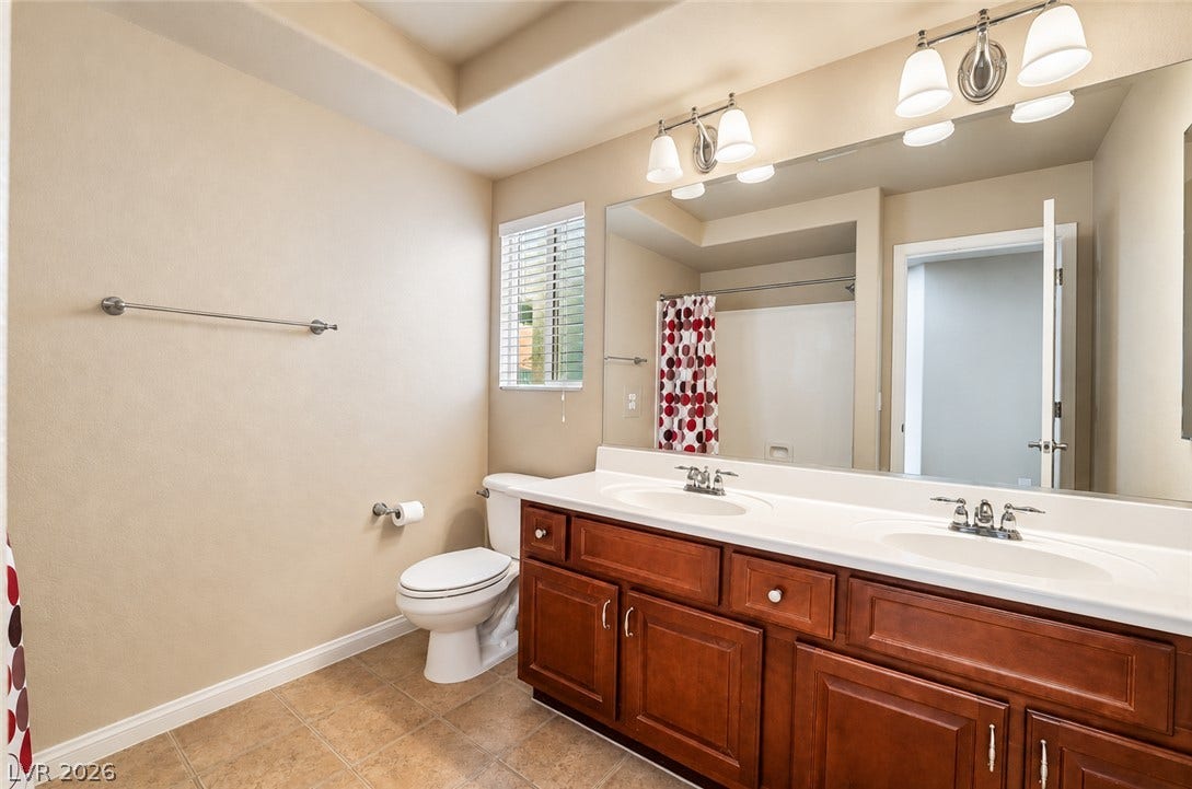 6771 Bravura Court, Las Vegas, NV 89139 Double vanities and tile flooring elevate this well-appointed bathroom.