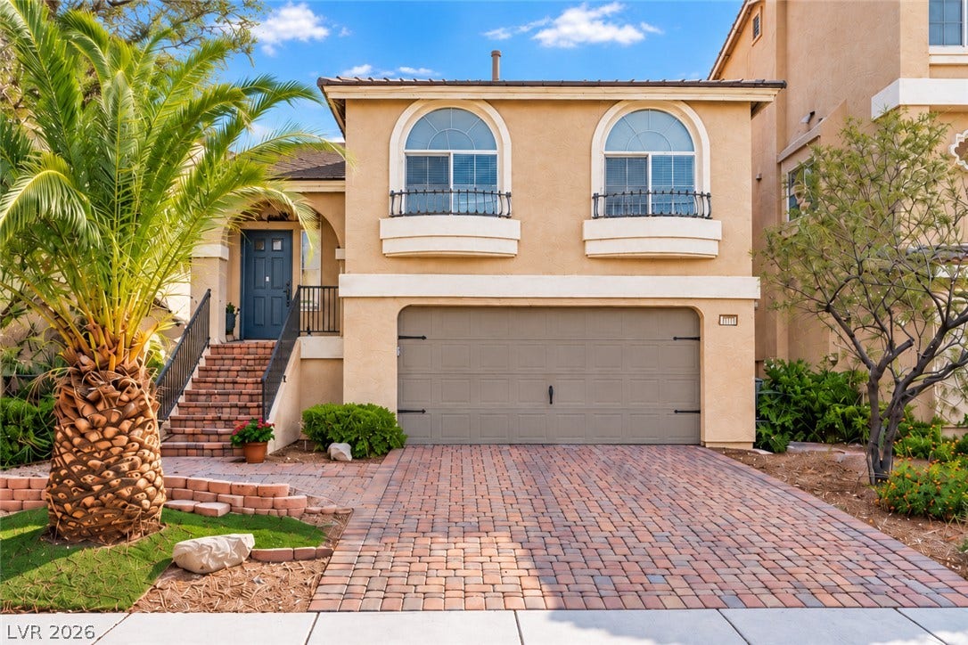6771 Bravura Court, Las Vegas, NV 89139 A paved driveway leads to a multi-level stucco home with a spacious garage.