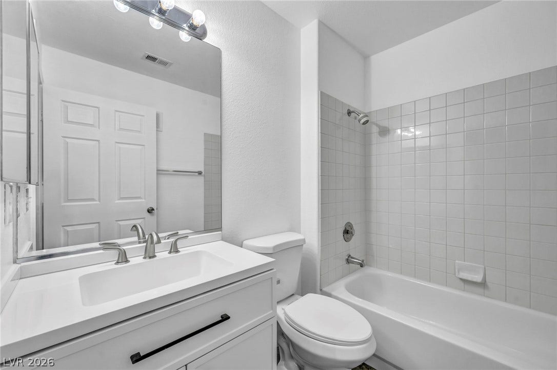 3613 Shawn Reynolds Court, #104, Las Vegas, NV 89129 Guest Bathroom - Tiled walls frame the tub shower combination adjacent to a clean vanity unit.