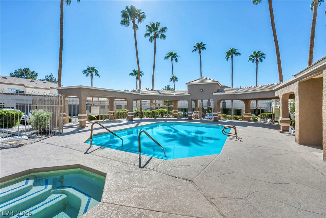3613 Shawn Reynolds Court, #104, Las Vegas, NV 89129 Palm trees frame a sparkling community pool and spa area under clear blue skies.
