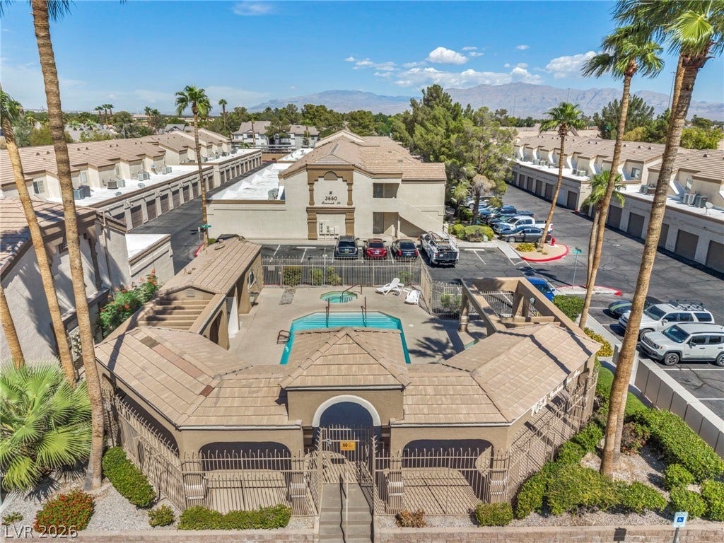 3613 Shawn Reynolds Court, #104, Las Vegas, NV 89129 A secured community swimming pool is surrounded by tiled roof structures and towering palms.