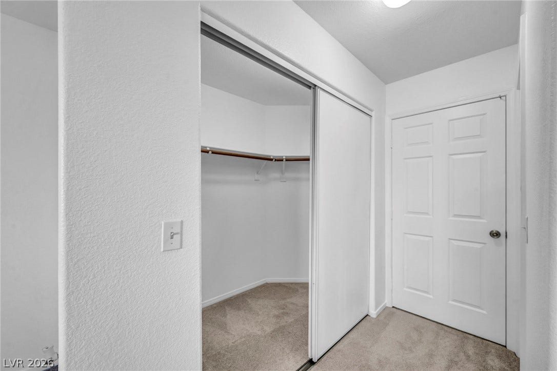 3613 Shawn Reynolds Court, #104, Las Vegas, NV 89129 Primary Bedroom - Sliding mirrored doors reveal a functional walk-in closet set over soft carpeting.