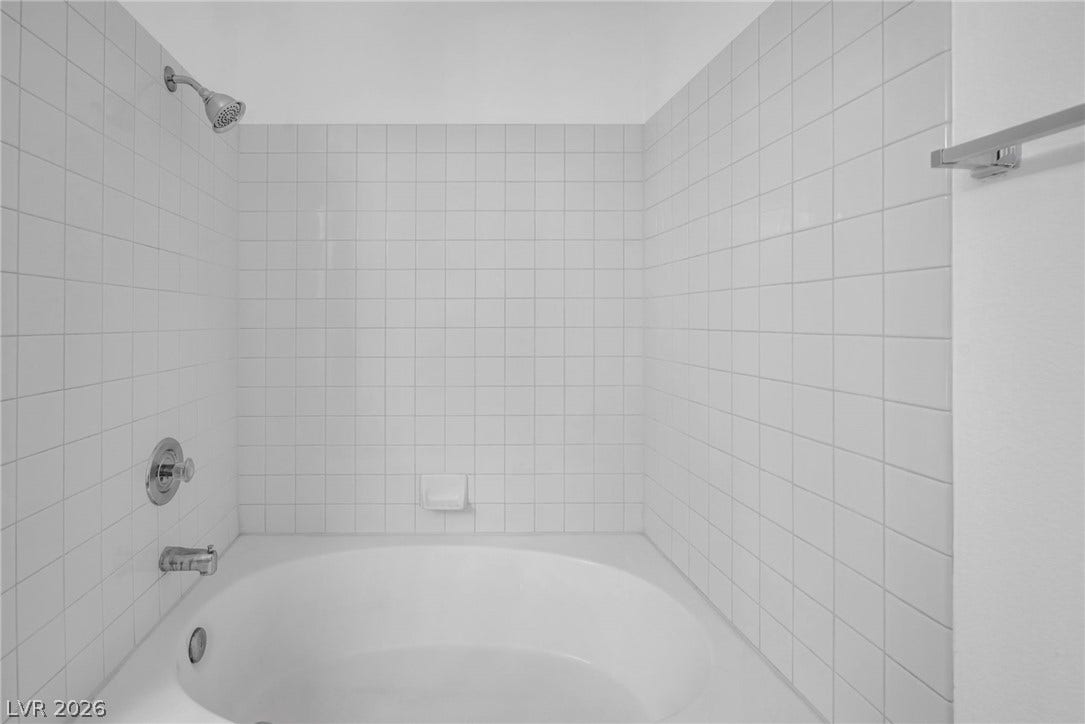 3613 Shawn Reynolds Court, #104, Las Vegas, NV 89129 Crisp white tiling wraps around a classic shower and soaking tub combination.