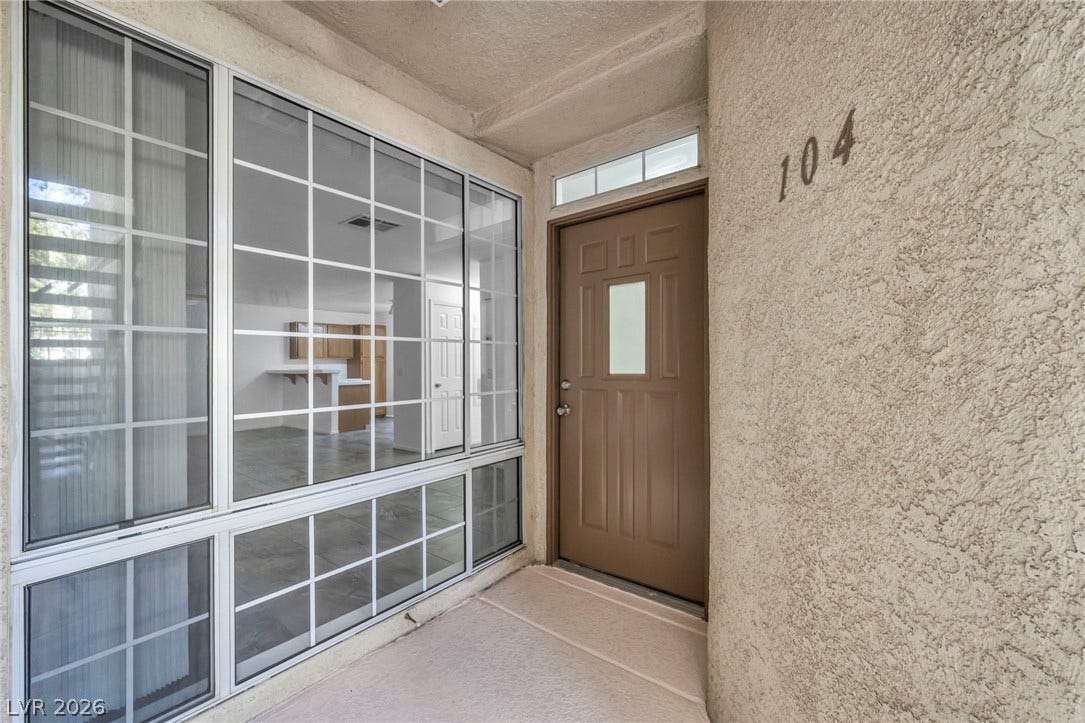 3613 Shawn Reynolds Court, #104, Las Vegas, NV 89129 A welcoming entryway features textured stucco walls alongside large gridded windows.