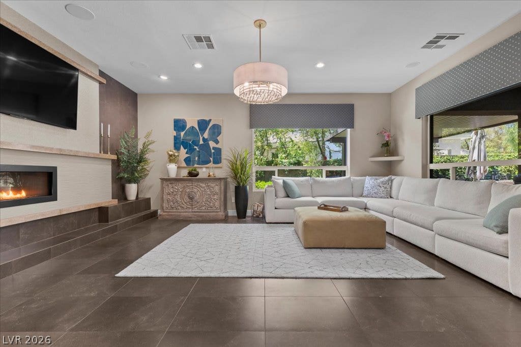 2985 American River Lane, Las Vegas, NV 89135 Bright living room featuring a cozy fireplace, tile flooring and natural light.