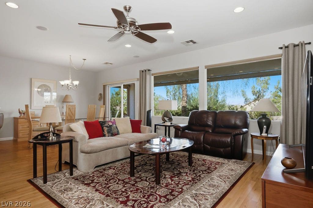 2510 Hamonah Drive, Henderson, NV 89044 Generous windows frame green outdoor views in an airy, open-concept living area with wood floors.