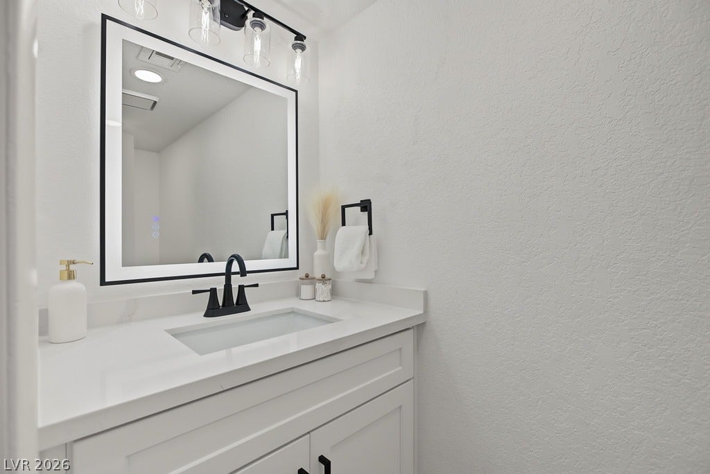 2371 Pickwick Drive, Henderson, NV 89014 An elegant vanity features clean white cabinetry paired with a sleek solid surface countertop.