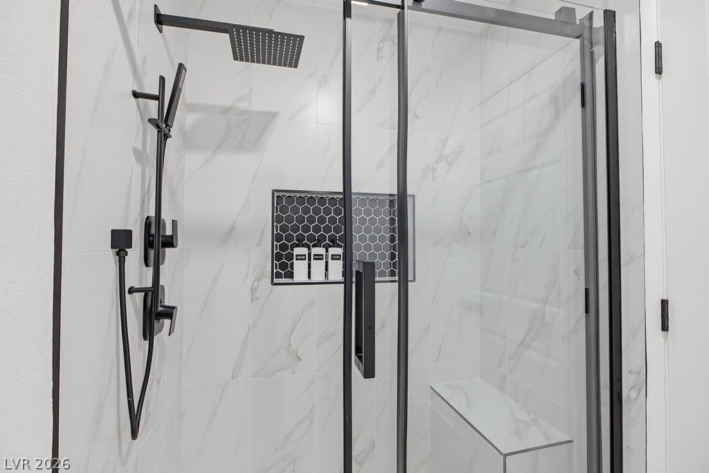2371 Pickwick Drive, Henderson, NV 89014 A modern walk-in shower features marble-patterned tile, matte black fixtures, and a built-in bench.