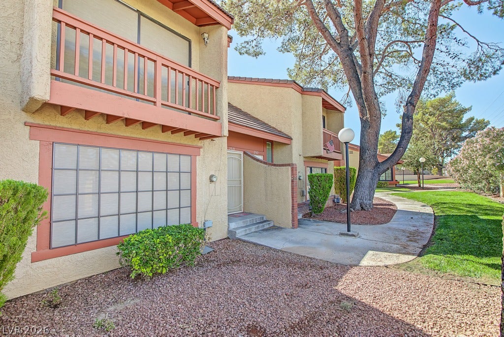 2371 Pickwick Drive, Henderson, NV 89014 Mature trees shade a paved walkway leading past stucco exteriors with private balconies.