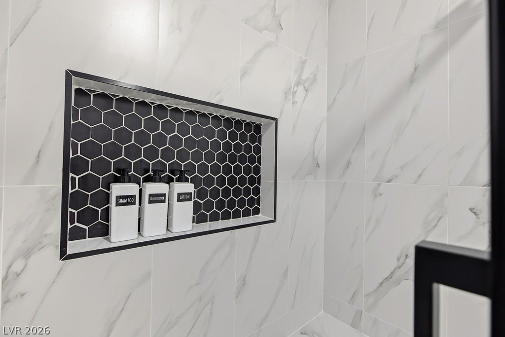 2371 Pickwick Drive, Henderson, NV 89014 Crisp marble-patterned wall tiles frame a built-in shower niche detailed with dark hexagonal accents.