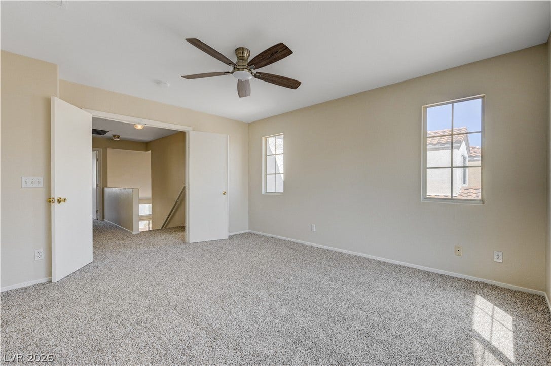 2706 Guidance Court, North Las Vegas, NV 89031 Double doors open to a spacious bedroom featuring wall-to-wall carpeting and multiple windows.
