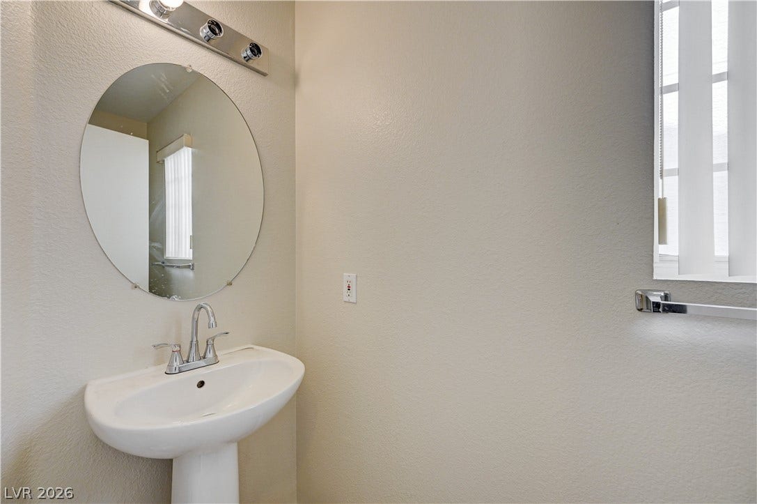 2706 Guidance Court, North Las Vegas, NV 89031 A classic pedestal sink sits beneath a round mirror in this tidy powder room.