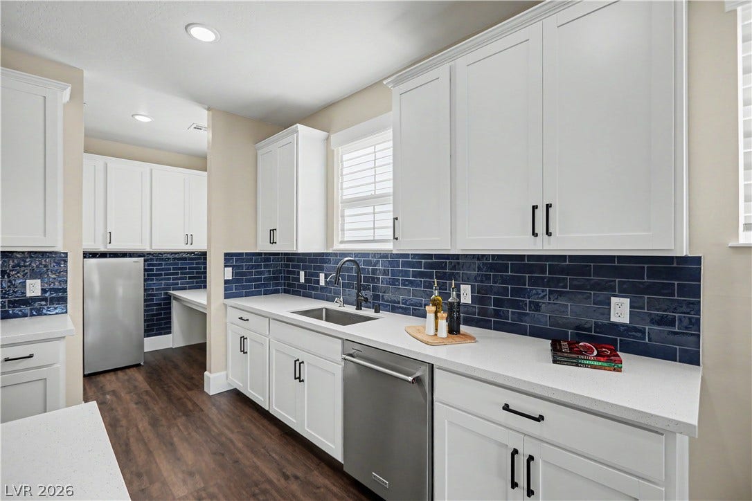 2555 Hampton Road, #11210, Henderson, NV 89052 The sink sits beneath a sunny window, with a sleek black pull down faucet and an upgraded KitchenAid stainless dishwasher close at hand.