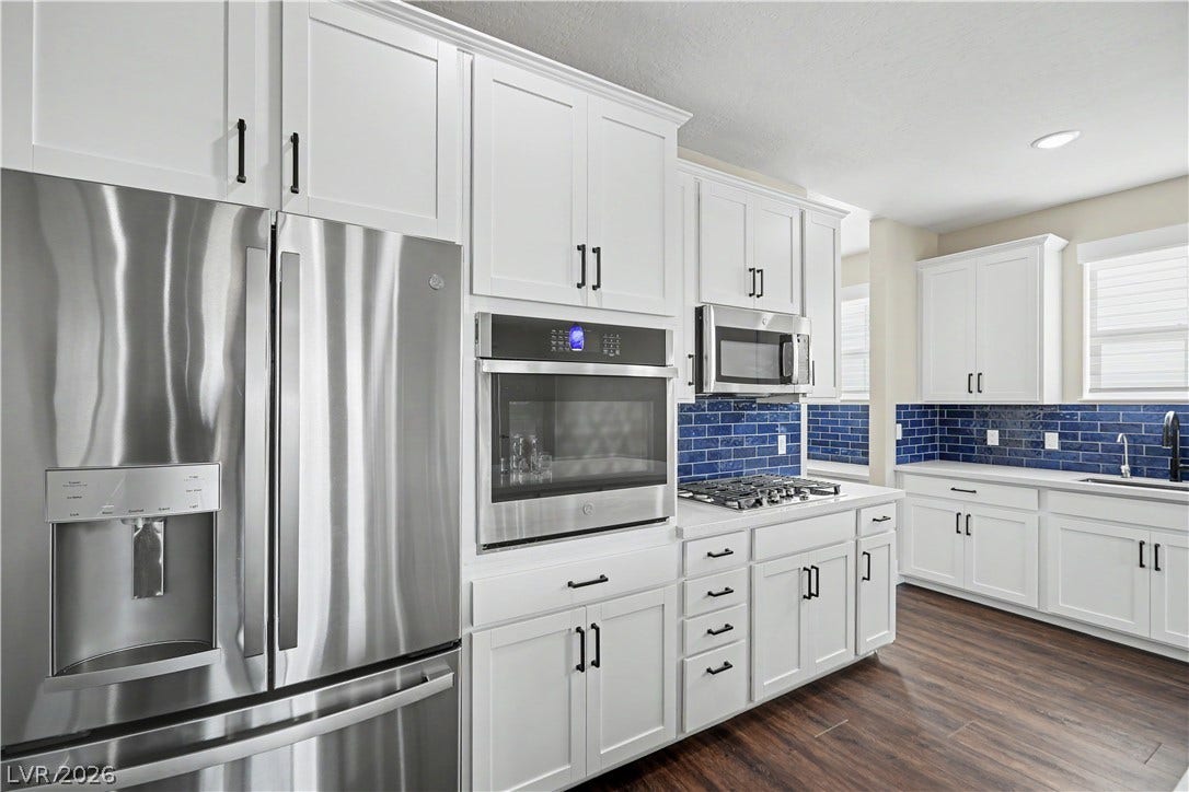 2555 Hampton Road, #11210, Henderson, NV 89052 Crisp white cabinetry with black hardware, a gas cooktop and a stunning navy backsplash make this kitchen as stylish as it is functional.