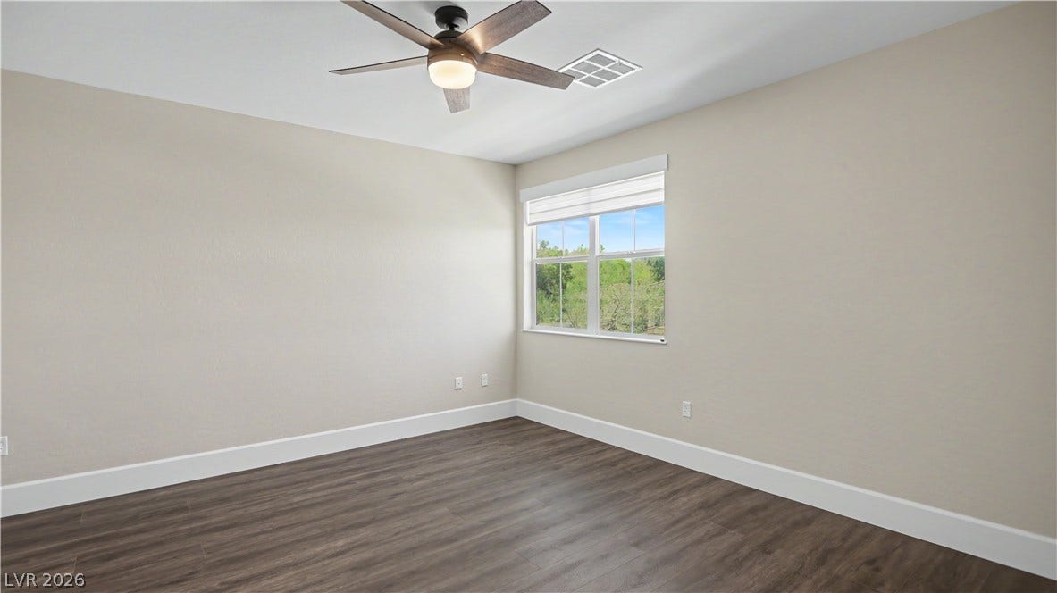 2555 Hampton Road, #11210, Henderson, NV 89052 The second bedroom offers a ceiling fan, wood-inspired LVP flooring and a window framing lush green treetop views.