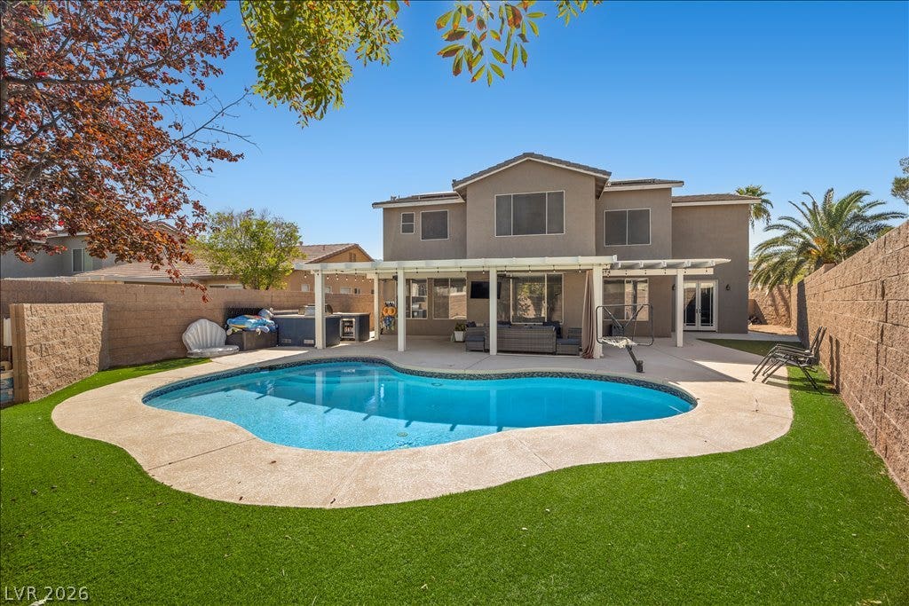 2386 Flute Avenue, Henderson, NV 89052 An inviting backyard oasis features a shimmering private pool beneath a covered patio.