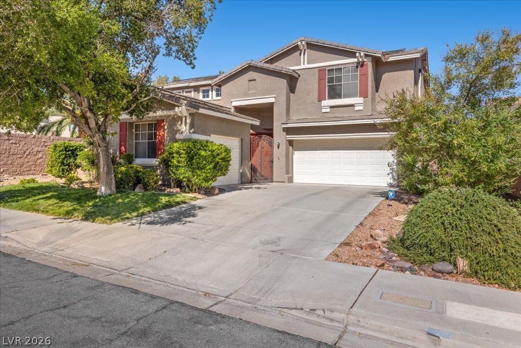 2386 Flute Avenue, Henderson, NV 89052 Mature trees shade the concrete driveway leading up to this two-story stucco home.