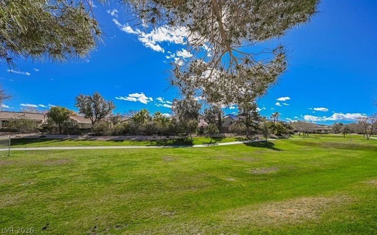 2386 Flute Avenue, Henderson, NV 89052 A paved walking trail winds through manicured green space under a bright blue sky.