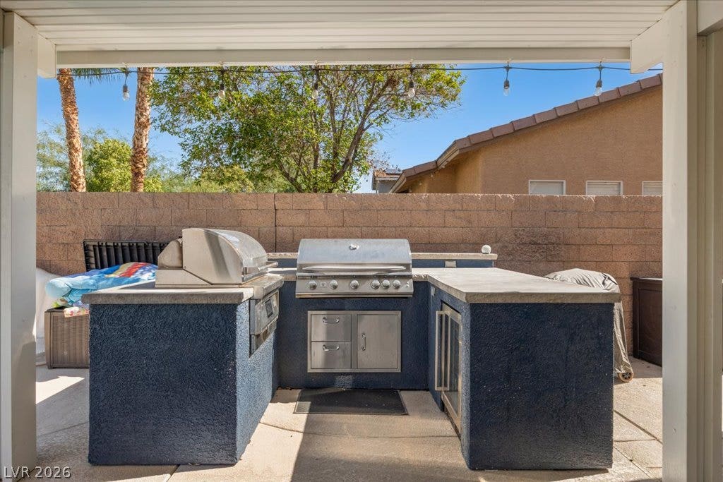 2386 Flute Avenue, Henderson, NV 89052 An outdoor kitchen features durable stone counters and premium cooking equipment under a covered patio.