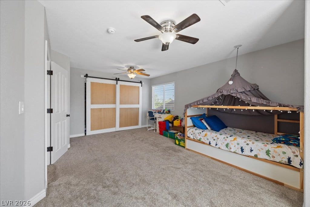 2386 Flute Avenue, Henderson, NV 89052 Plush carpeting underfoot and sliding barn doors define this comfortable, light-filled bedroom.