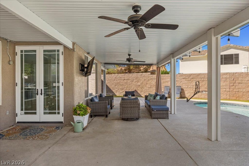 2386 Flute Avenue, Henderson, NV 89052 Shaded concrete patio features double French doors leading inside and overlooks a backyard pool.