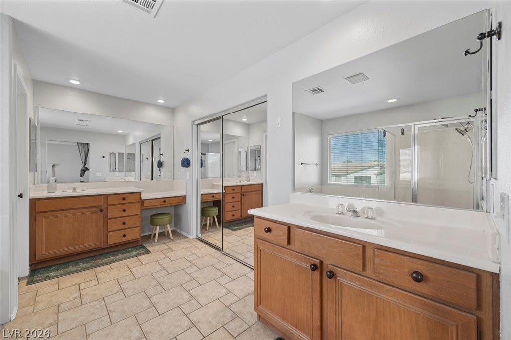 2386 Flute Avenue, Henderson, NV 89052 Ample wooden cabinetry and neutral tile flooring define this highly functional dual-vanity bathroom space.