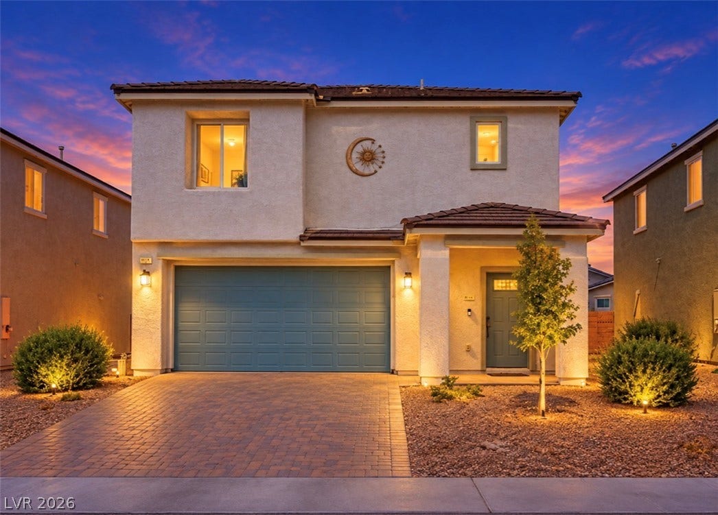 2713 Concord Street, North Las Vegas, NV 89030 Warm exterior lighting accents this modern stucco home featuring a paved driveway and tiled roof.