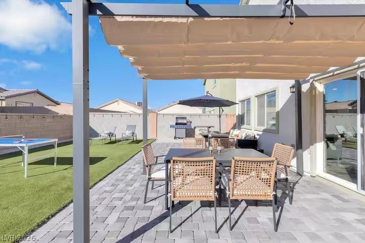 2713 Concord Street, North Las Vegas, NV 89030 An inviting paved patio sits beneath a structured shade sail alongside a green backyard.