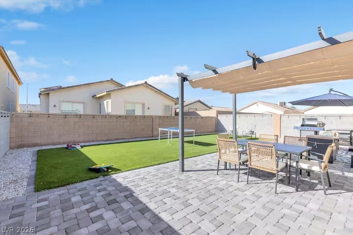 2713 Concord Street, North Las Vegas, NV 89030 A spacious paved patio features a shade pergola alongside a clean synthetic lawn.