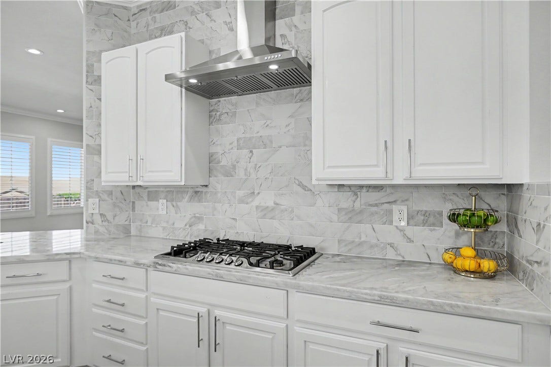 2073 Fountain City Street, Henderson, NV 89052 Elegant marble tile runs from countertop to ceiling, creating a stunning backdrop for the gas cooktop and stainless range hood.