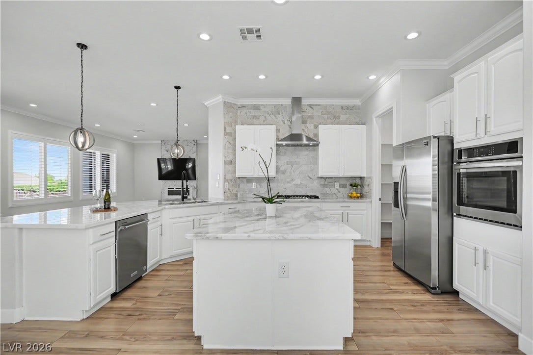 2073 Fountain City Street, Henderson, NV 89052 This stunning kitchen features two islands, gleaming stainless appliances, a built-in wall oven, and a walk in panty, all wrapped in crisp white cabinetry.