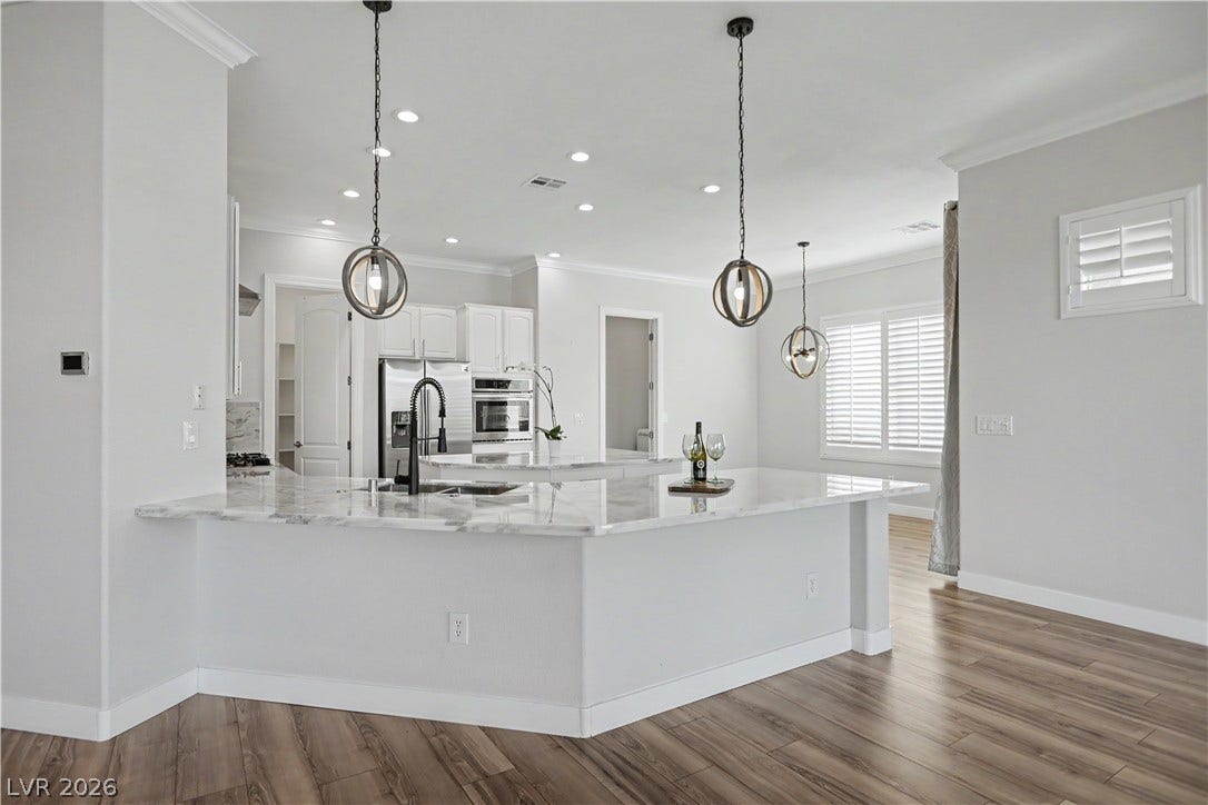 2073 Fountain City Street, Henderson, NV 89052 The heart of the home features an oversized wraparound island with a marble countertop, black pull-down faucet and orb pendant lighting.