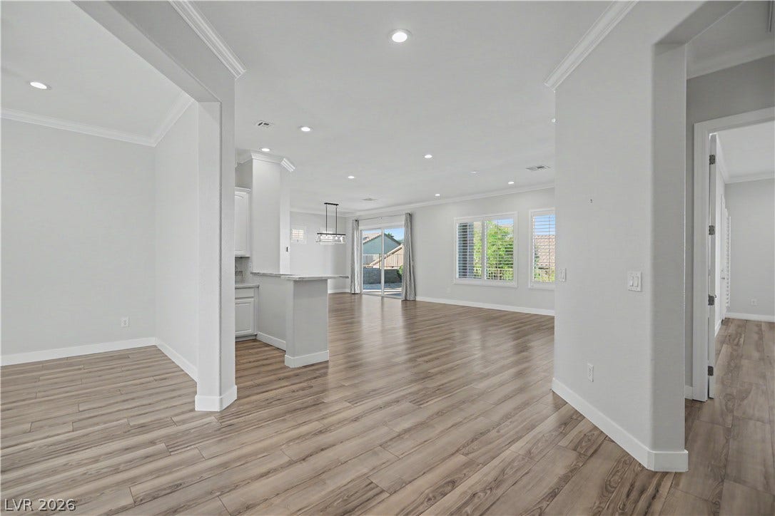2073 Fountain City Street, Henderson, NV 89052 From the foyer, the home opens up to a bright, open-concept layout with crown molding, recessed lighting, and wood-look laminate flooring throughout.