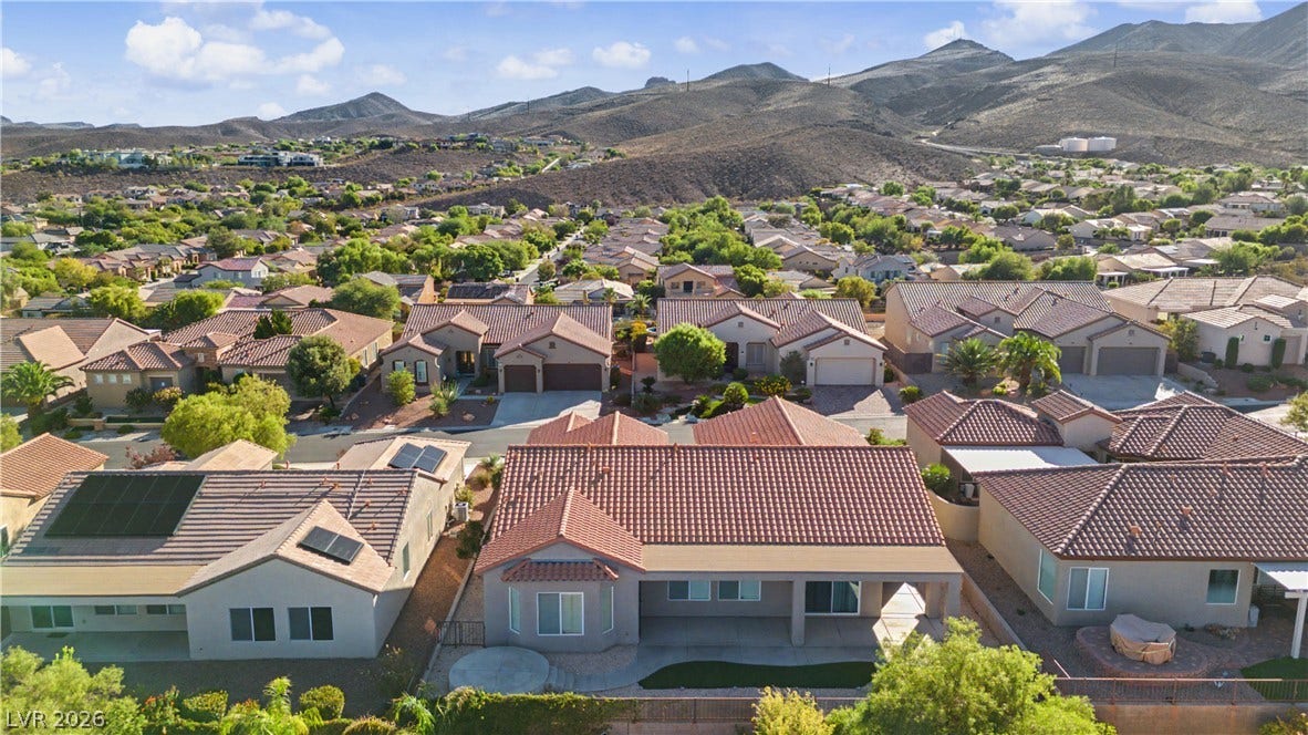 2073 Fountain City Street, Henderson, NV 89052 The backyard offers an extended patio, a circular raised paver seating area, a strip of green turf, desert landscaping, all with mountain views.