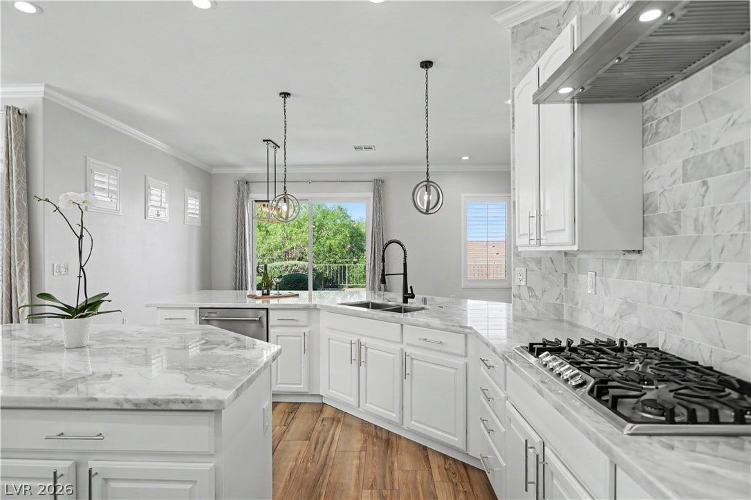 2073 Fountain City Street, Henderson, NV 89052 Bright, open, and beautifully updated this kitchen pairs white cabinetry with marble counters with views of the backyard.