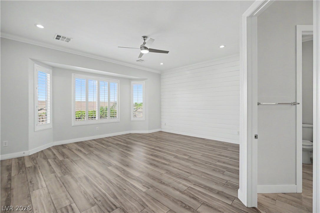 2073 Fountain City Street, Henderson, NV 89052 The spacious primary retreat features a bay window with plantation shutters, a shiplap accent wall, modern ceiling fan and crown molding.