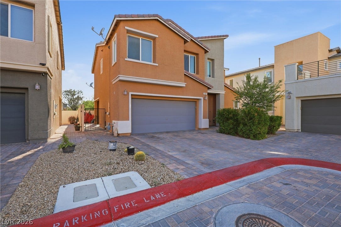 7057 Millers Run Street, North Las Vegas, NV 89084 Multi-level modern stucco exterior showcases a two-car garage integrated alongside paved driveway detailing.