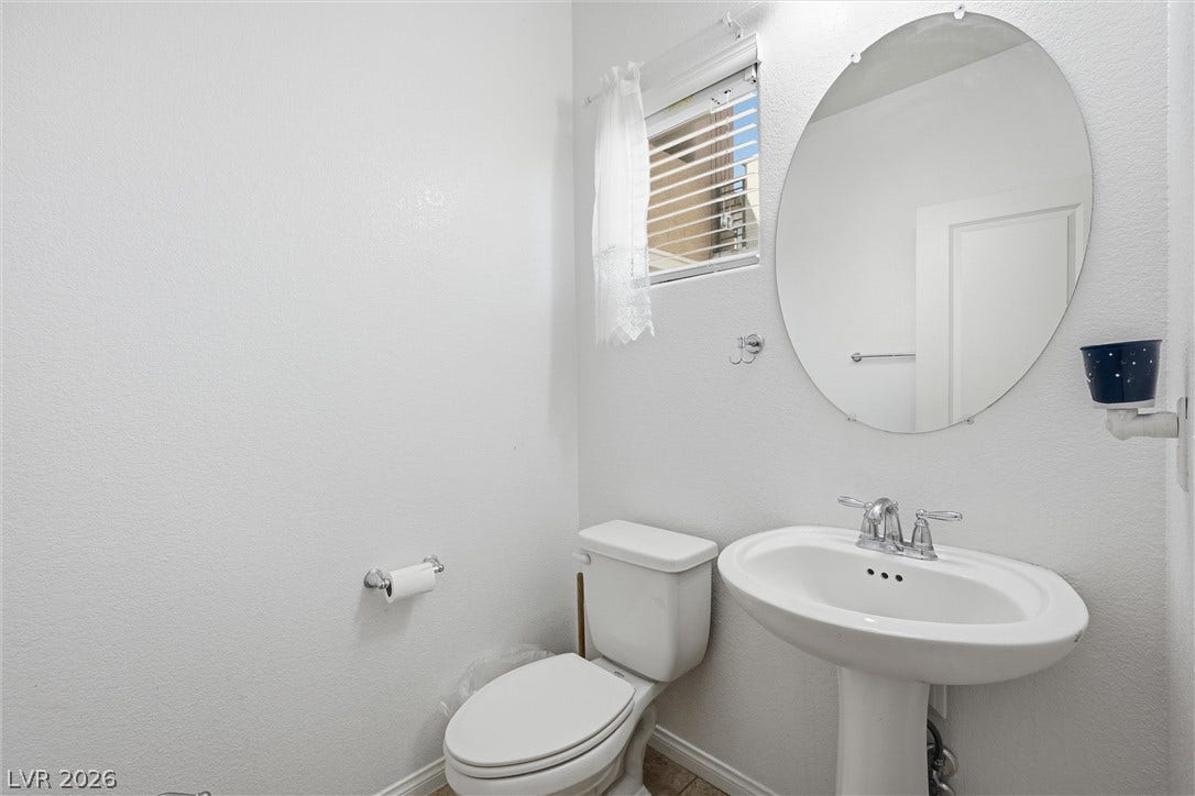 7057 Millers Run Street, North Las Vegas, NV 89084 A classic pedestal sink paired with an oval wall mirror enhances this half bathroom.