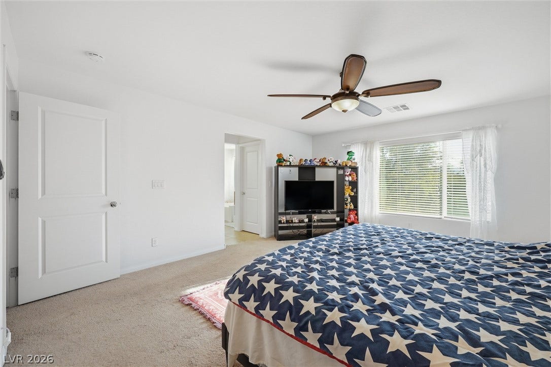 7057 Millers Run Street, North Las Vegas, NV 89084 Plentiful natural light filters through a wide window into this carpeted bedroom.