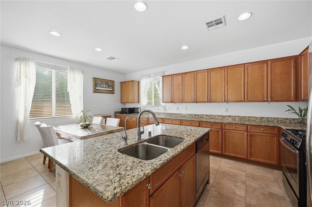 7057 Millers Run Street, North Las Vegas, NV 89084 Ample wooden cabinetry and stone countertops anchor this functional cooking space with a central island.