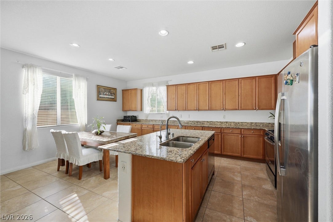 7057 Millers Run Street, North Las Vegas, NV 89084 Ample wooden cabinetry and stone countertops anchor this spacious kitchen and informal dining area.