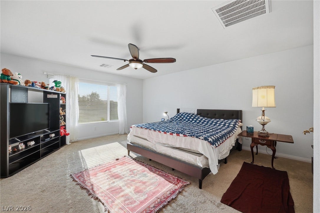 7057 Millers Run Street, North Las Vegas, NV 89084 Plentiful natural light streams across the carpeted flooring of this comfortable bedroom.