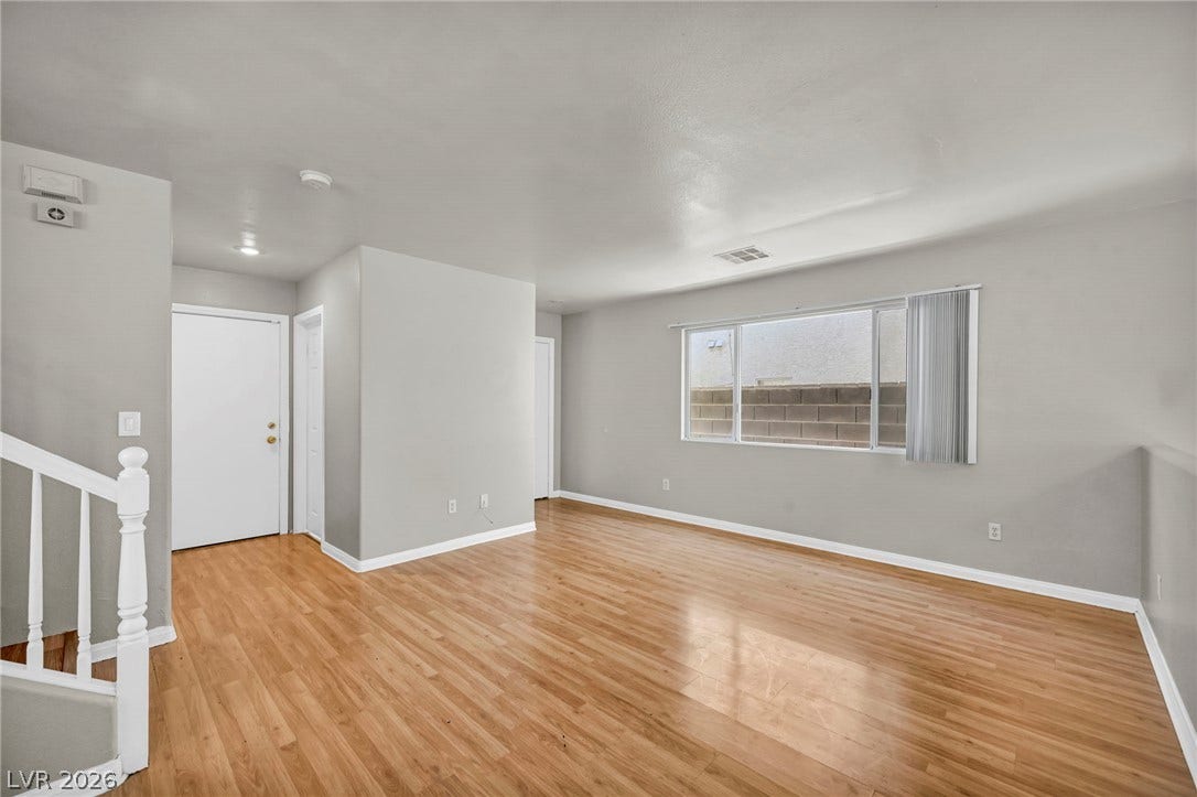 Warm wood flooring and natural light from wide windows define this versatile living area.