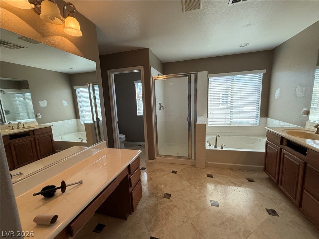 5904 Gold Horizon Street, North Las Vegas, NV 89031 Stone tile flooring and a separate soaking tub anchor this spacious main bathroom layout.