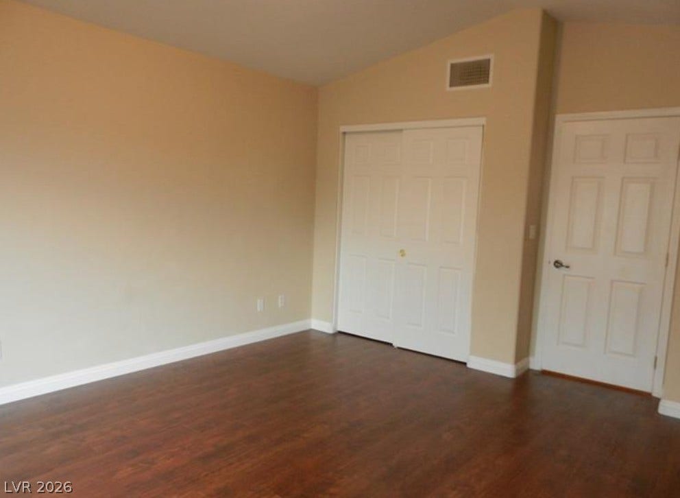 4421 Oberlander Avenue, North Las Vegas, NV 89031 Rich hardwood flooring anchors this versatile bedroom space featuring a vaulted ceiling and ample closet storage.