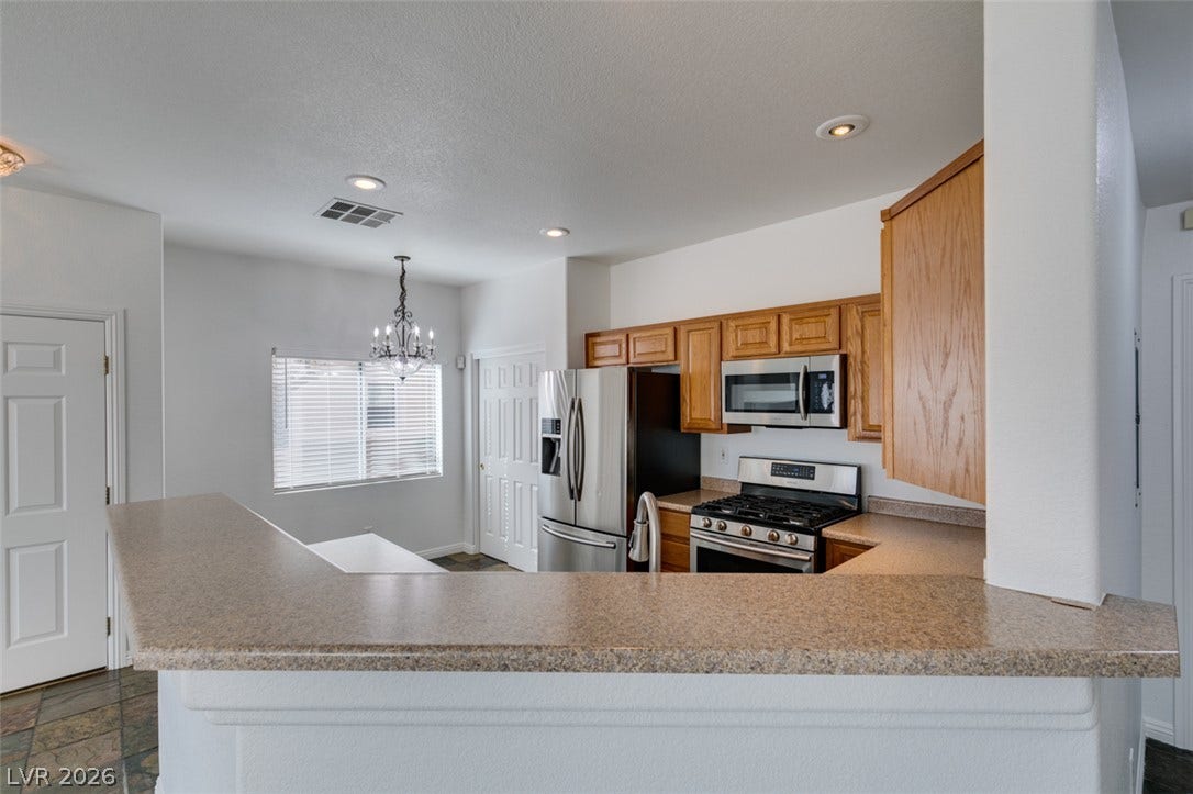 3612 Indigo Flower Street, #2, North Las Vegas, NV 89084 Smooth laminate countertops define a functional breakfast bar opening to the kitchen space.