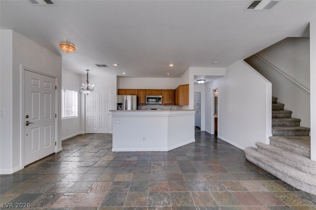 3612 Indigo Flower Street, #2, North Las Vegas, NV 89084 Earthy slate floor tiles ground this open interior layout leading to the central kitchen.
