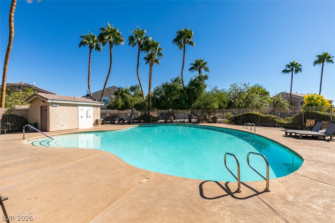 3612 Indigo Flower Street, #2, North Las Vegas, NV 89084 Towering palm trees frame the sparkling community swimming pool under clear desert skies.