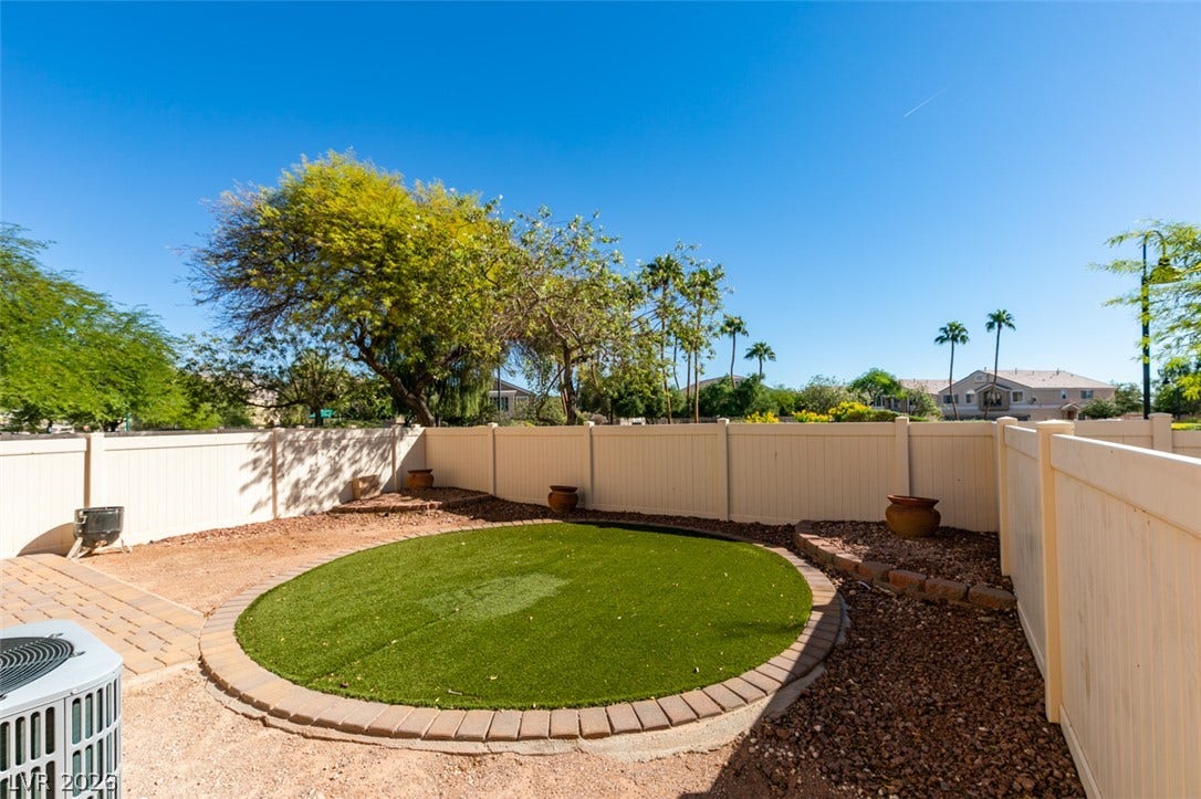 3612 Indigo Flower Street, #2, North Las Vegas, NV 89084 Mature trees frame a private fenced yard featuring a circular lawn and stone accents.