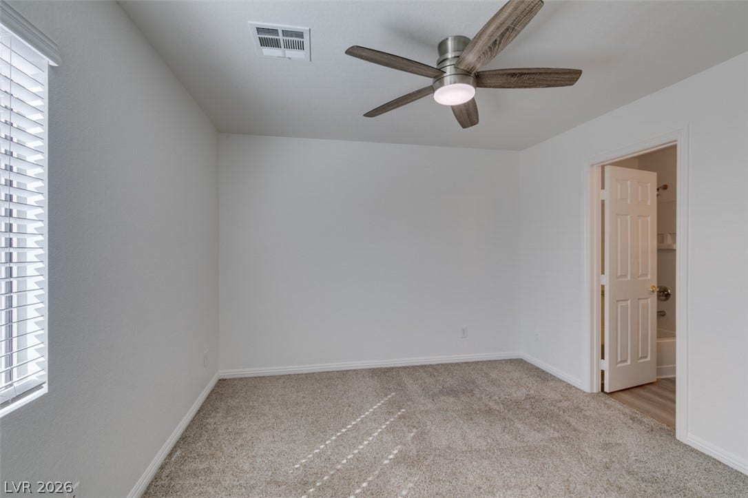 3612 Indigo Flower Street, #2, North Las Vegas, NV 89084 Plush carpeting anchors this quiet bedroom space featuring an attached bathroom access.